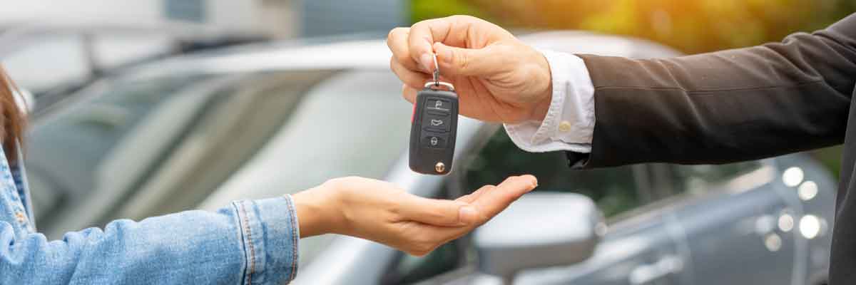 Two outstretched arms as one arm is dropping a set of car keys into the the others hand.