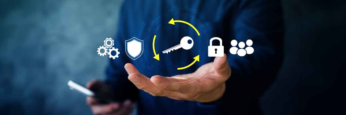 Person holding a smartphone with key management icons above an open hand, including a key, padlock, shield and users.